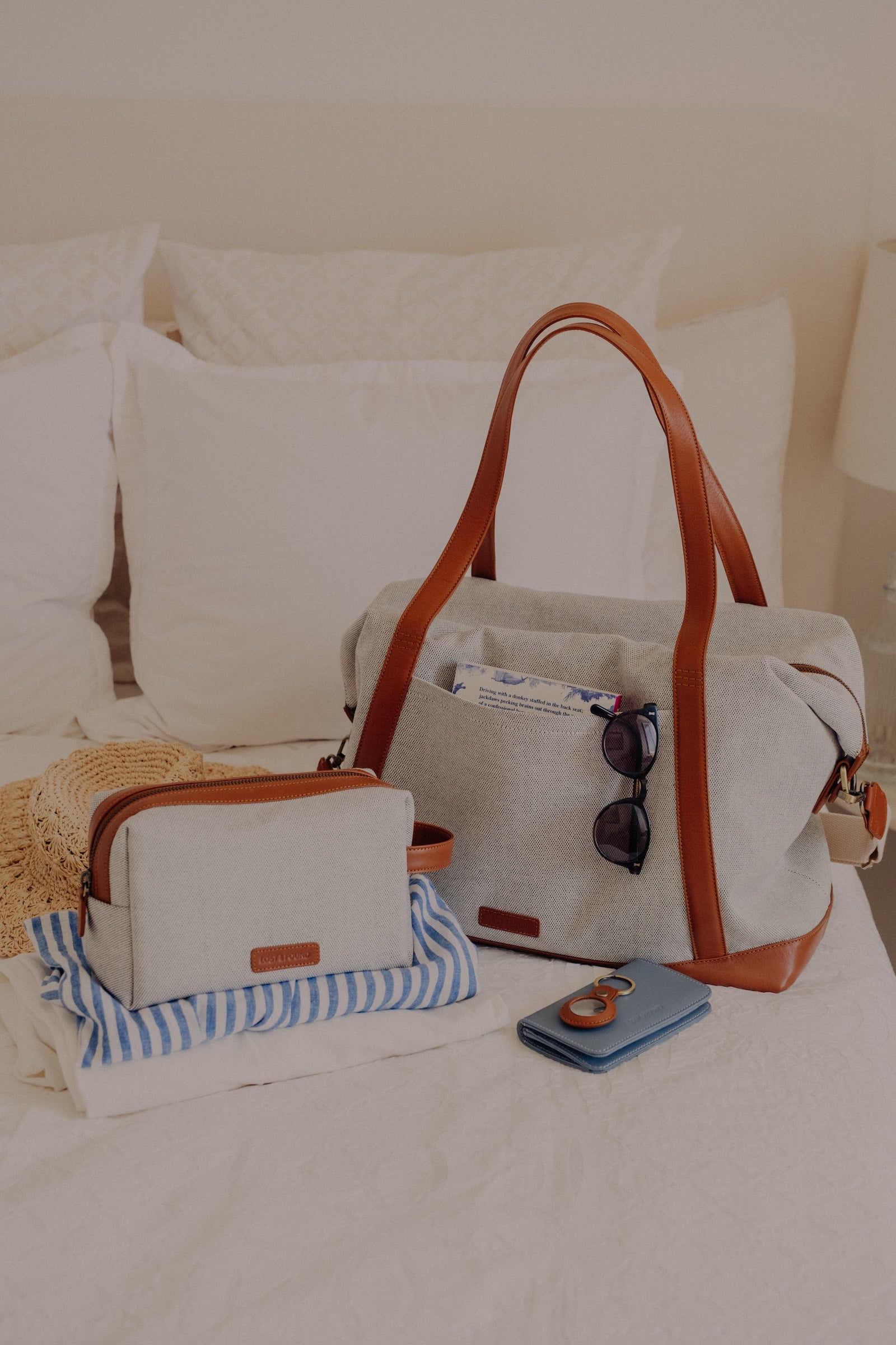 Weekender und Necessaire aus Canvas auf Bett mit weiteren Accessoires