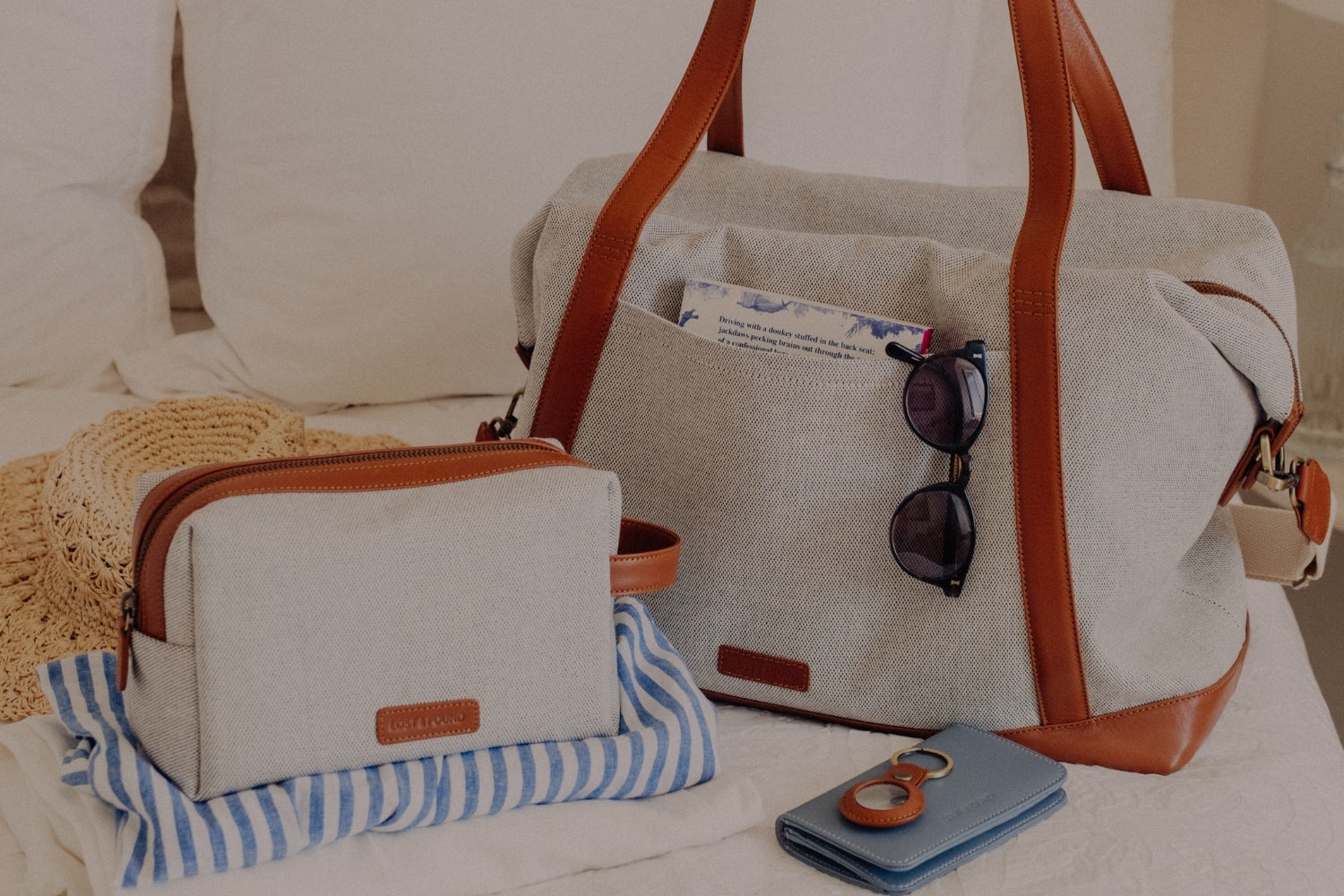 Weekender und Necessaire aus Canvas auf Bett mit weiteren Accessoires