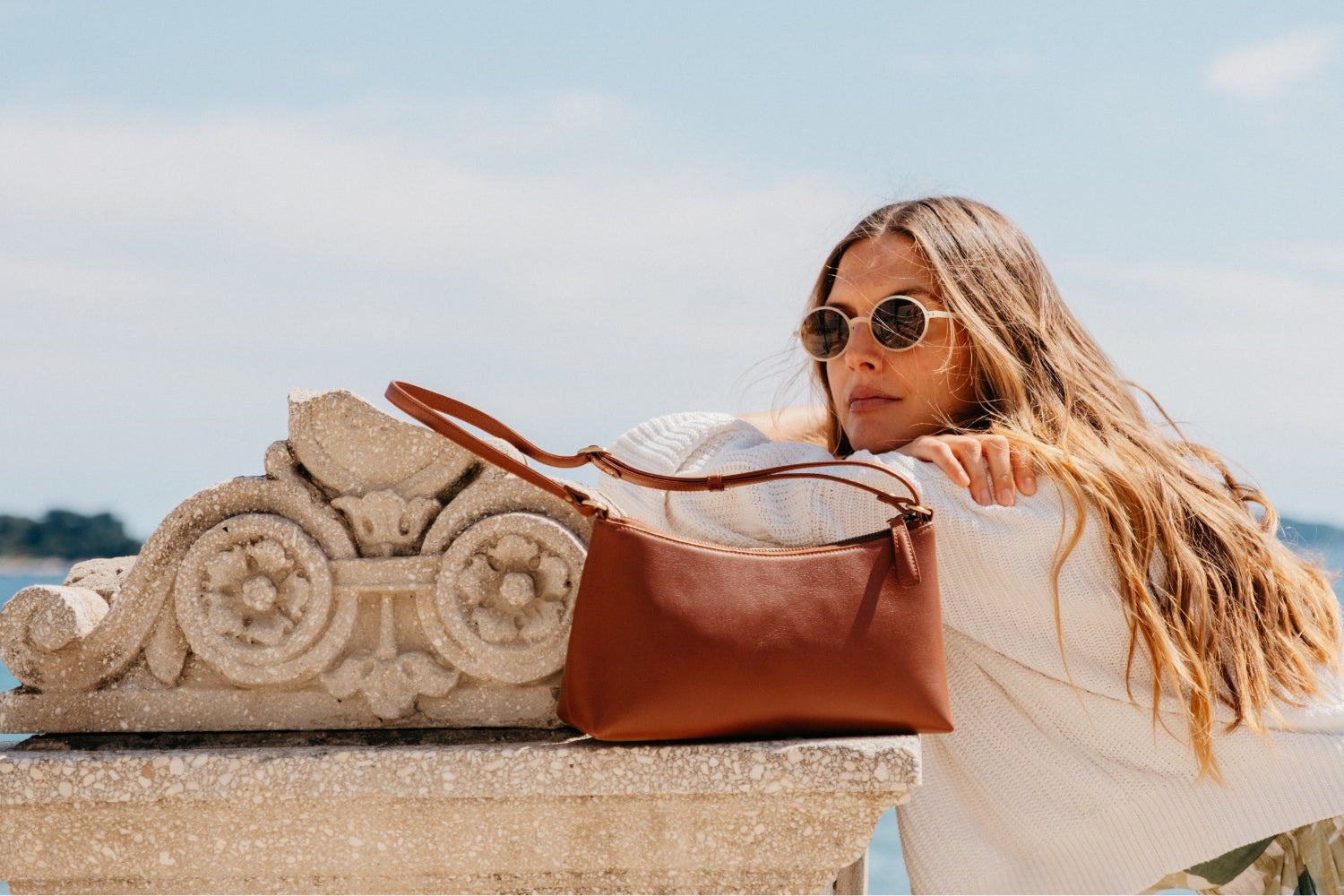 Easy Tasche in Whisky Braun auf Mauer mit lässig daran angelehnter Frau